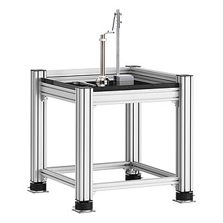a square, cube-shaped metrology table made of aluminium profiles, with thick black granite table top, mounted on black air-cushion vibro-mounts FLN, and with precision height marker, calliper and levelling element placed on the granite table top, isolated on white background