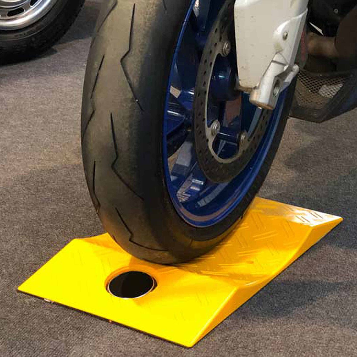 a yellow concave-shaped TyreGuard® tyre protector made of high-strength plastics, underneath a motorcycle tyre