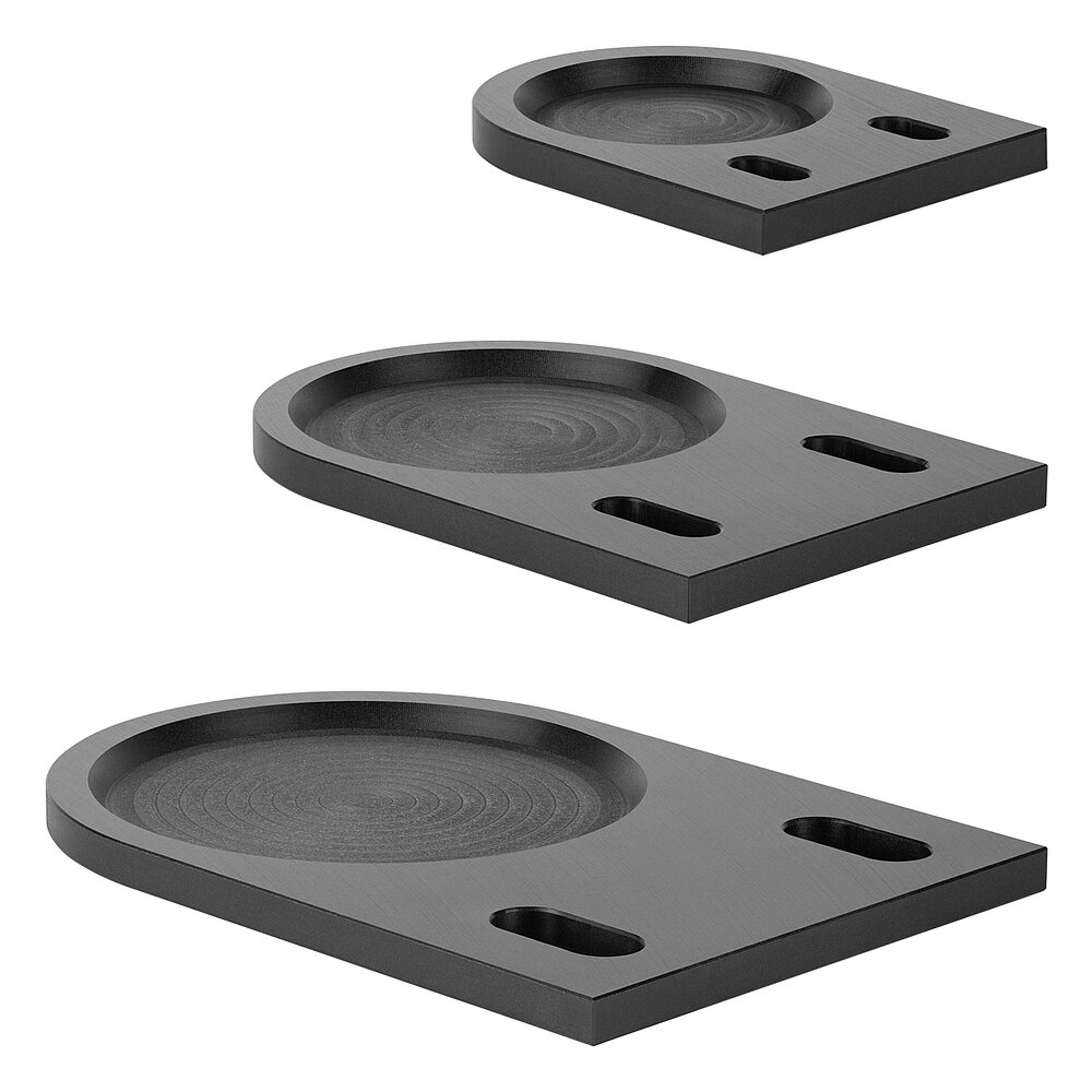 a selection of three differently-sized black floor-fixture plates for levelling elements, made of precision-milled composite material, in the slanted side view, isolated on white background